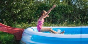 criança se jogando em piscina de plástico