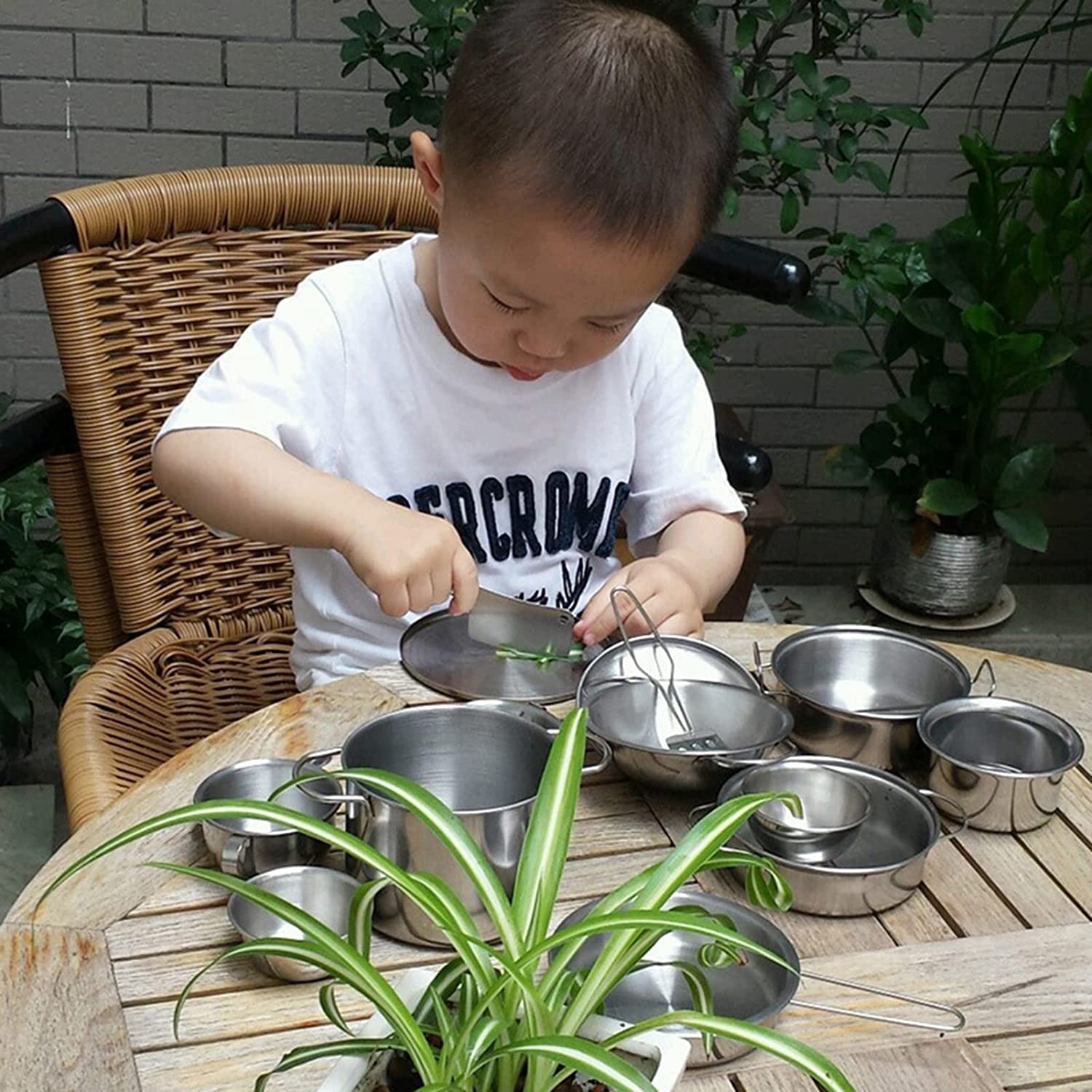 criança brincando com panelas de brinquedo de metal