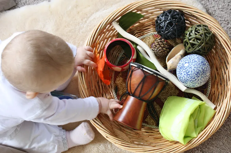 criança mexendo em cesto de materiais naturais com brinquedos