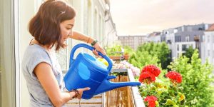 mulher regando plantas em varanda