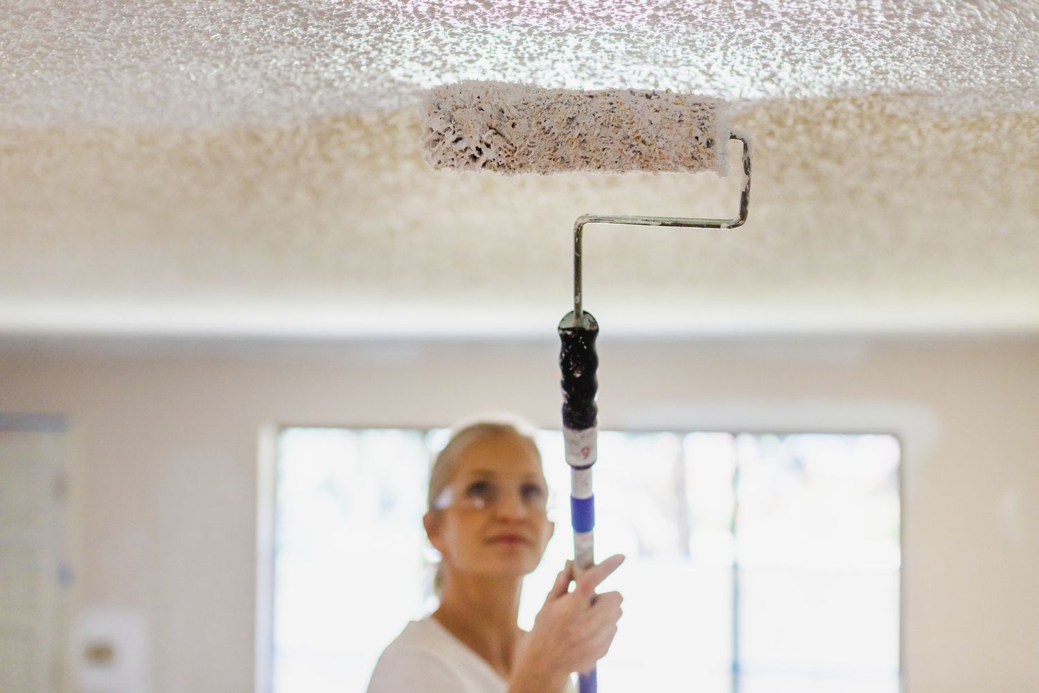 mulher pintando teto de cômodo da casa