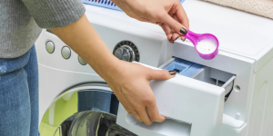 pessoa colocando sabão em dispenser da máquina de lavar