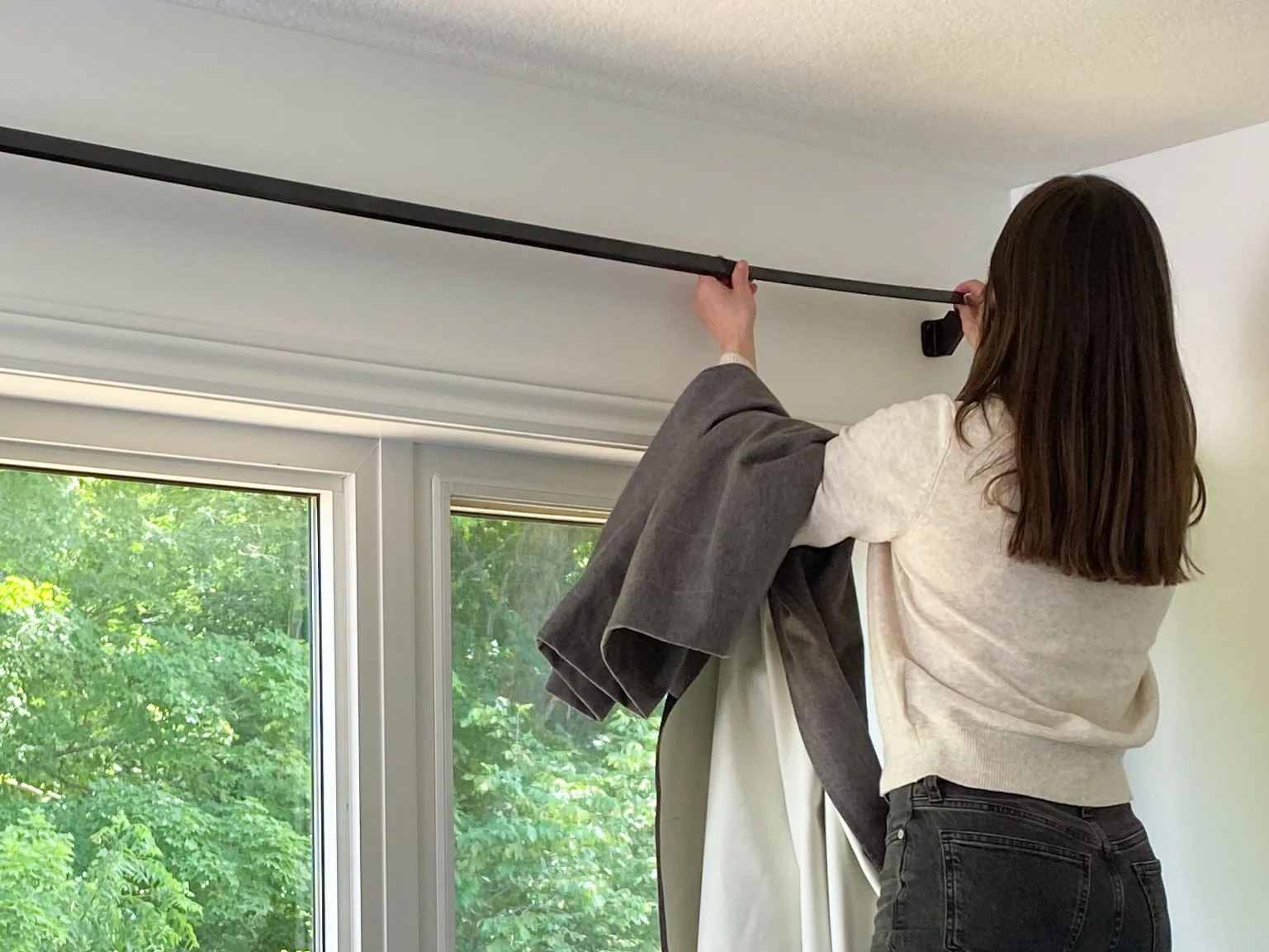 mulher instalando cortinas blackout