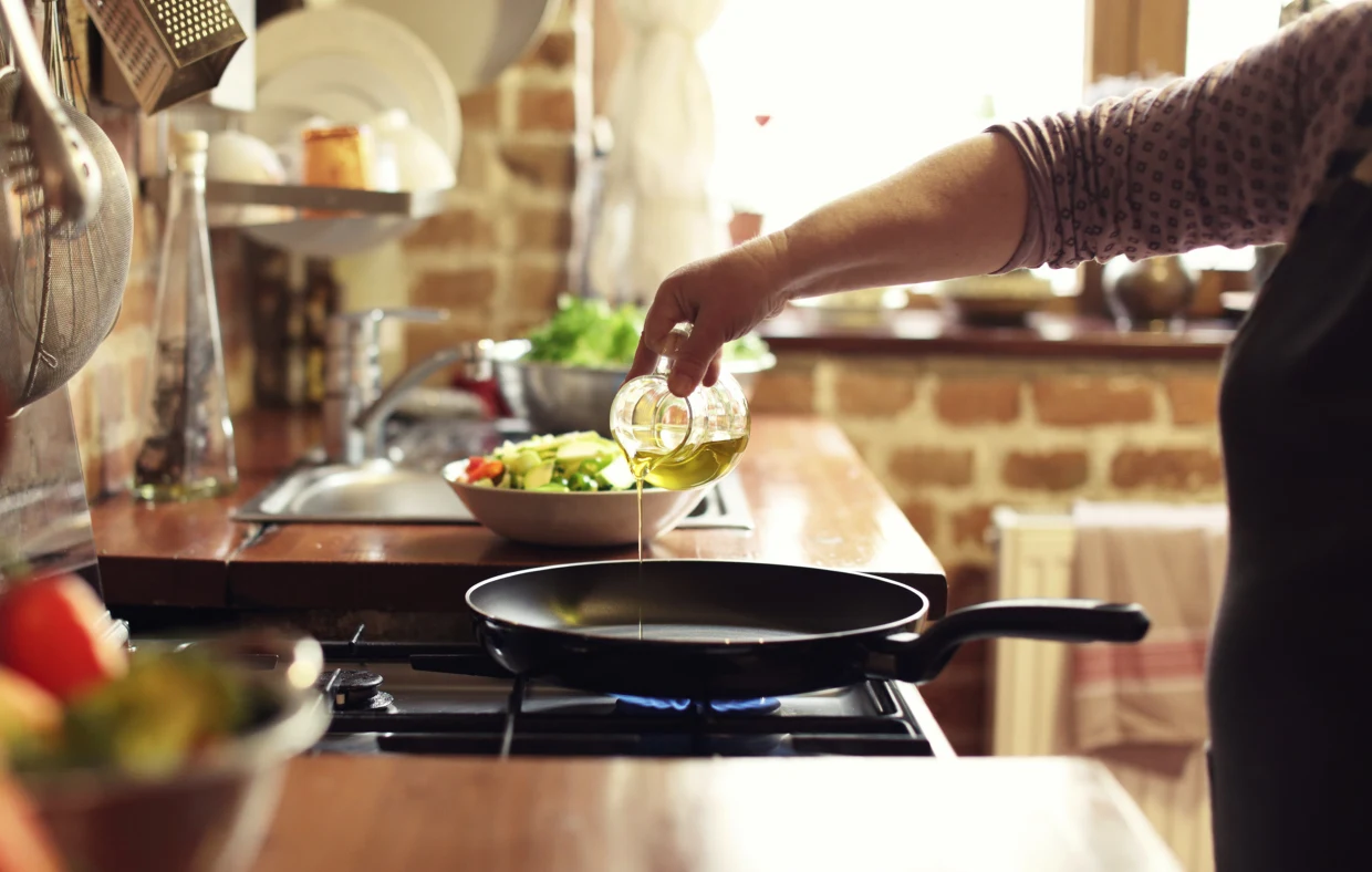 pessoa colocando óleo de cozinha em frigideira