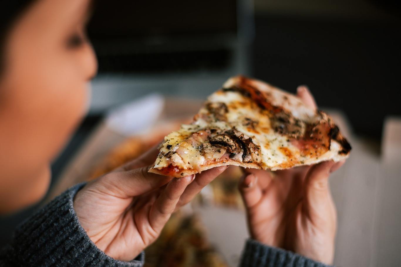 mulher com pedaço de pizza na mão