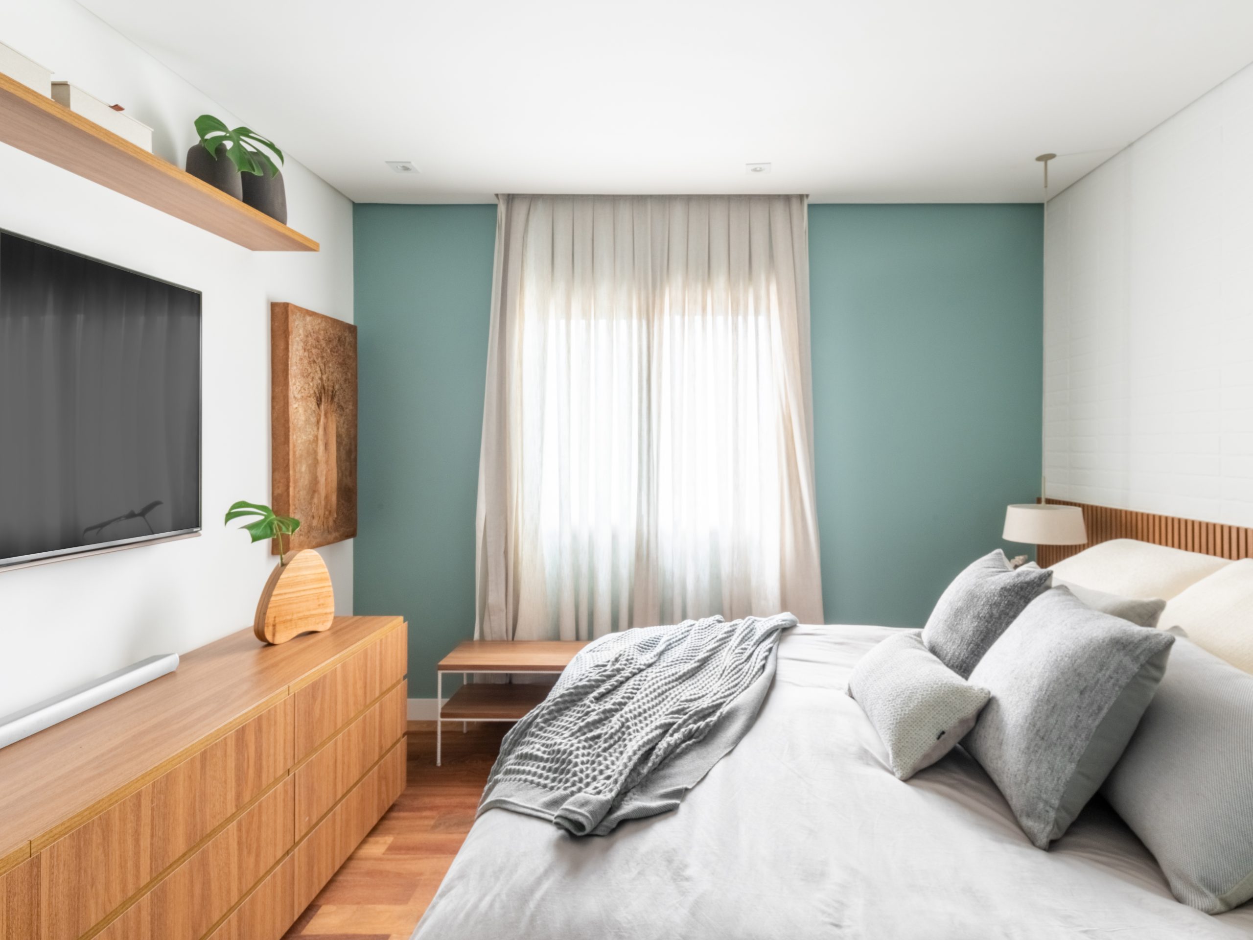 quarto principal de apartamento com parede de destaque em tom azul