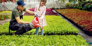 Jovem ensina menina a regar plantas (Foto: Freepik)