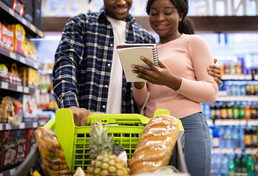 casal olhando lista de compras em supermercado