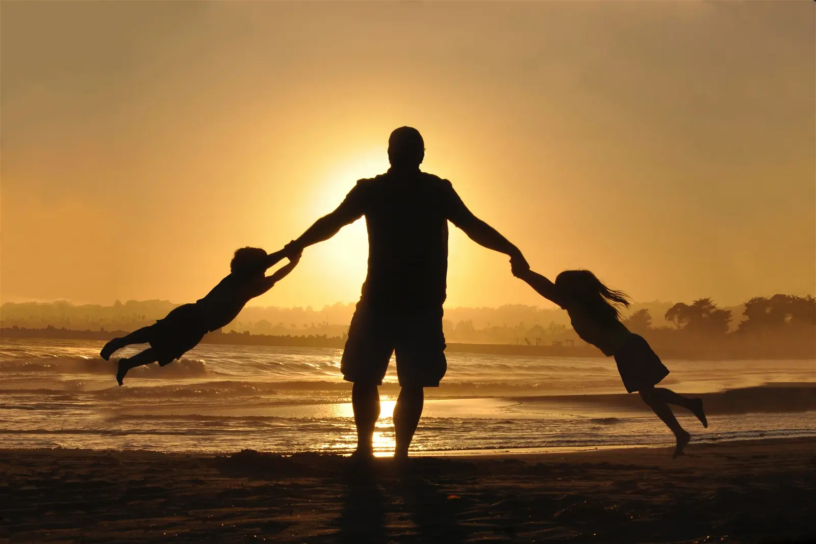 pai brincando com crianças na praia